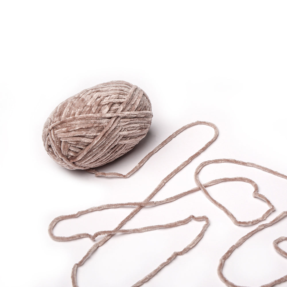 Ein Knäuel von Rico Design superflauschiges Garn mit losen Strängen, die eine Herzform auf weißem Hintergrund bilden - perfekt für häkelnde Projekte.