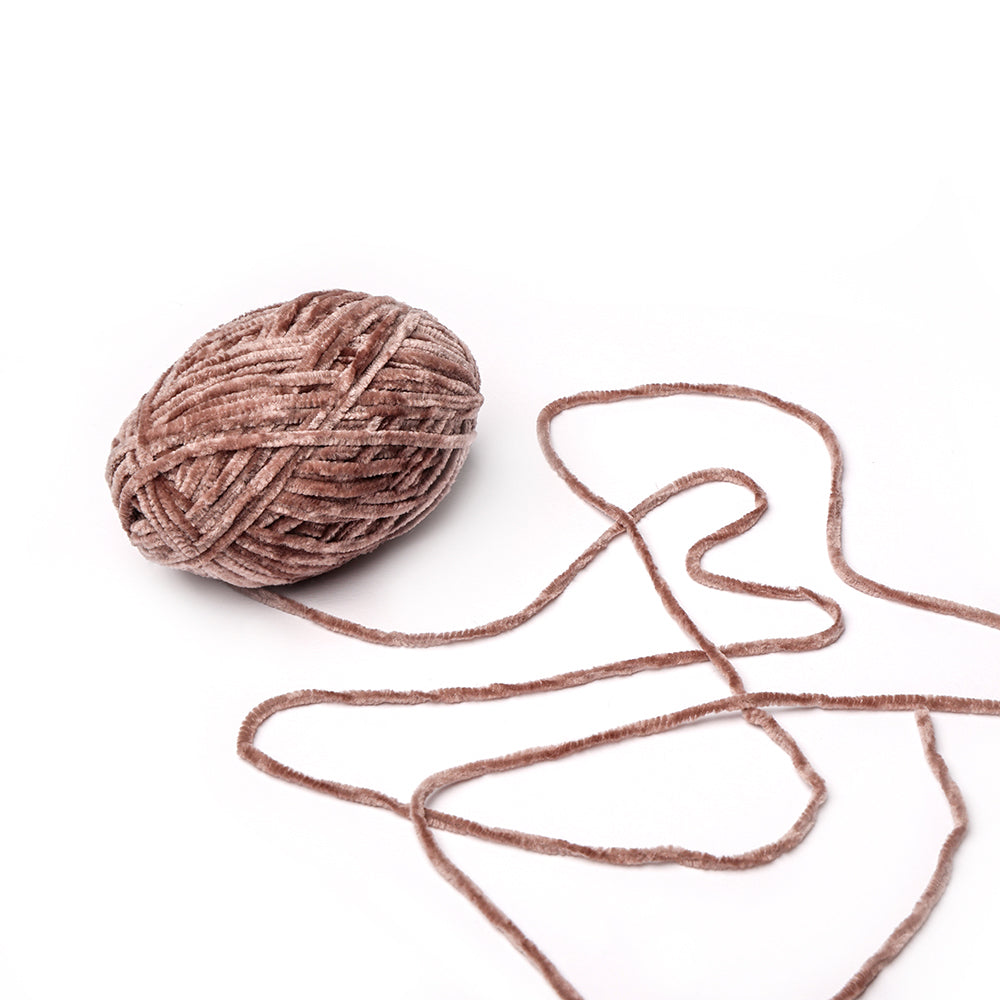 Ein weiches, braunes Knäuel Rico Design Chenille Garn mit einem losen Strang ruht auf einem weißen Hintergrund, ideal für Amigurumi-Häkelprojekte oder Handarbeiten mit farbechtem Garn.