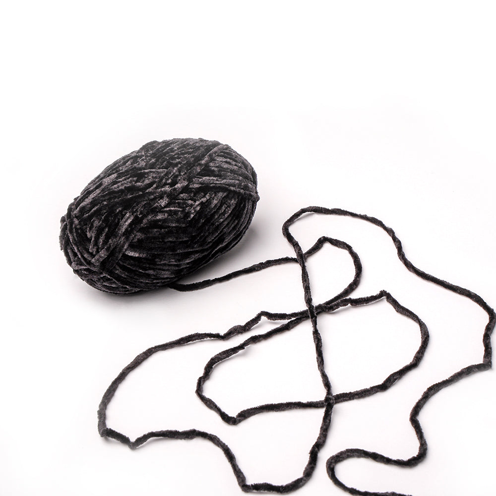 Ein Knäuel schwarzes, superflauschiges Rico Design Garn mit einem losen Strang auf weißem Grund - perfekt für Häkel- und Kuschelprojekte.