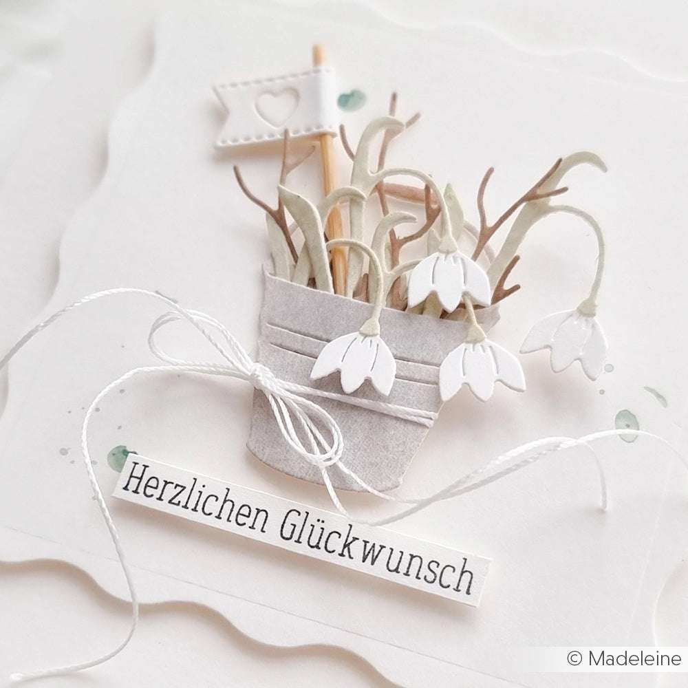 Handgemachte Karte von Alexandra Renke mit Papierschneeglöckchen im Topf, zarter Perlenschnur, einer kleinen Fahne und dem Text "Herzlichen Glückwunsch".