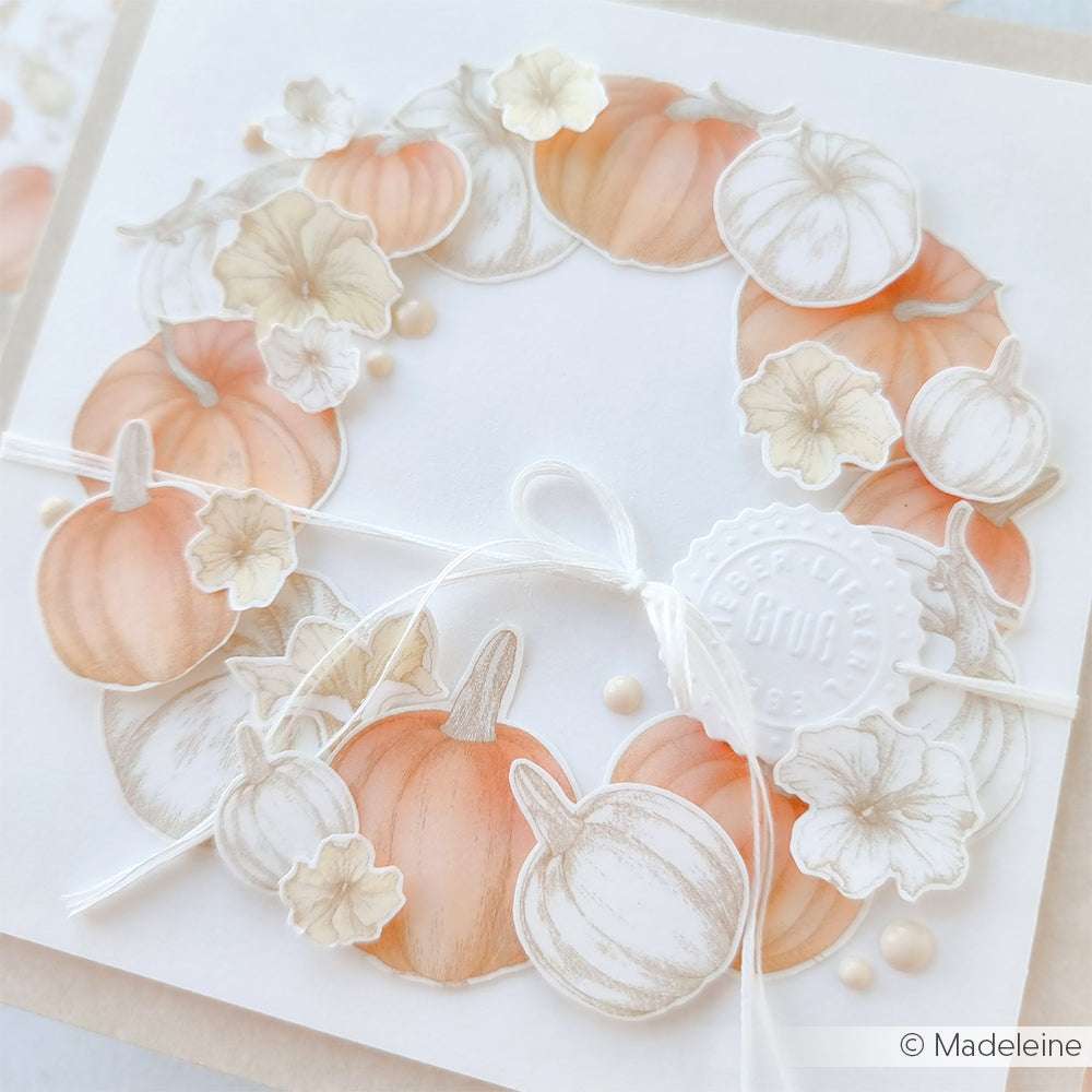 Eine weiße Karte von Alexandra Renke ist mit einem pastellfarbenen Kürbis und einem Blumenkranz verziert, mit einer Kumihimo-Schnur gebunden und mit einem Wachssiegel versehen.