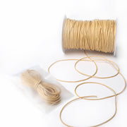 Eine Spule und ein Päckchen beige gewachste Baumwollkordel von Alexandra Renke, mit etwas Kordel auf einer weißen Oberfläche - ideal für Dekoration oder Schmuckherstellung Projekte.