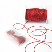 Eine Spule roter gewachster Baumwollkordel von Alexandra Renke mit etwas loser Kordel, sowie eine versiegelte Packung mit weiterer roter Kordel - ideal für Dekoration oder Schmuckherstellung - auf weißem Hintergrund.