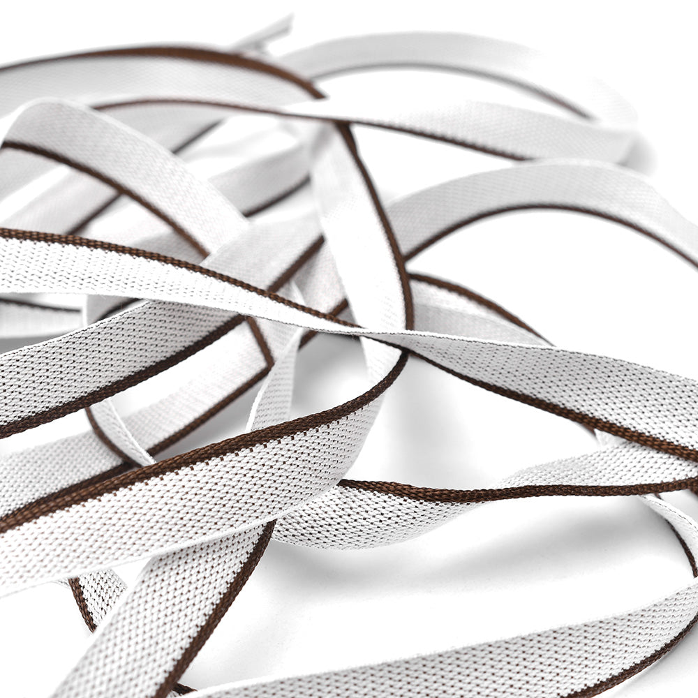 Weiße und braune flache Schnürsenkel von Alexandra Renke, die an Kapitalband auf Hardcover-Büchern erinnern, sind verknotet und vor einem sauberen weißen Hintergrund ausgebreitet.