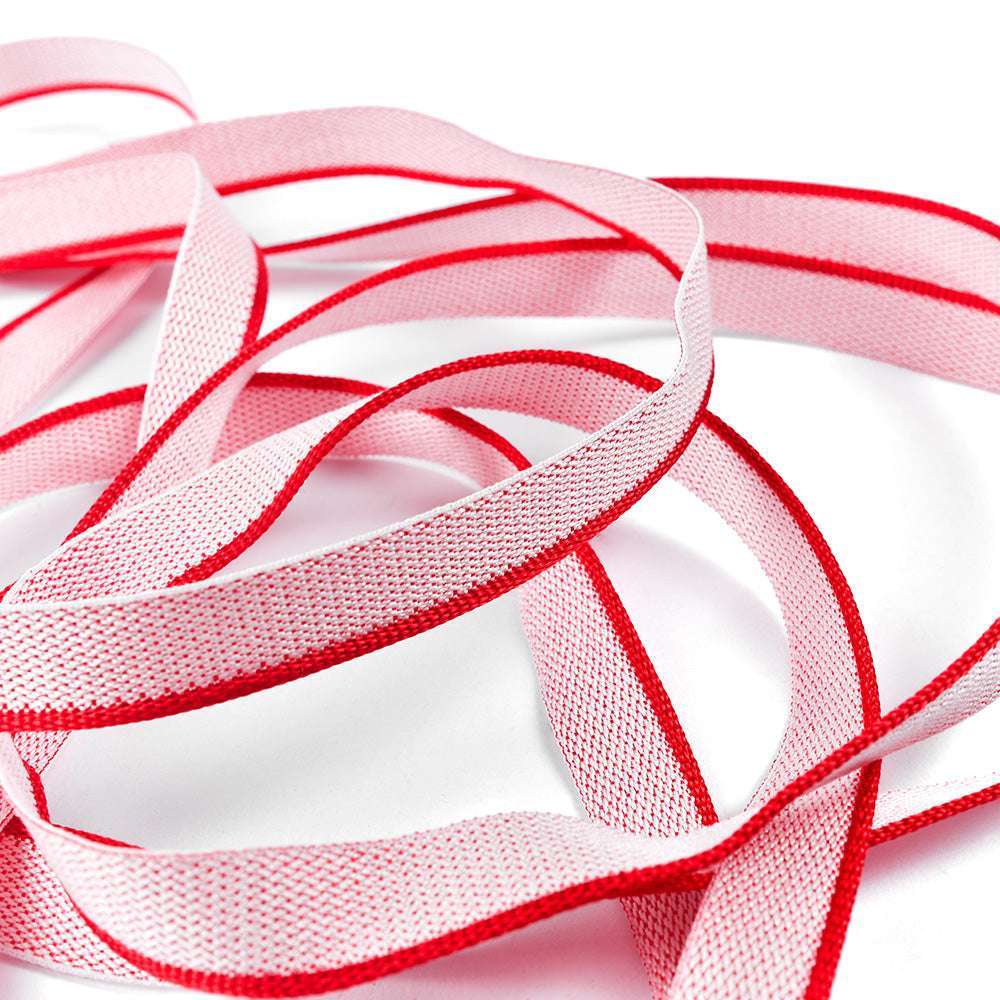 Ein weißes Band mit roten Rändern von Alexandra Renke, das an ein Kapitalband erinnert, ist locker gewickelt und überlappt sich auf weißem Hintergrund - ein elegantes Detail, das man oft bei gebundenen Büchern sieht.