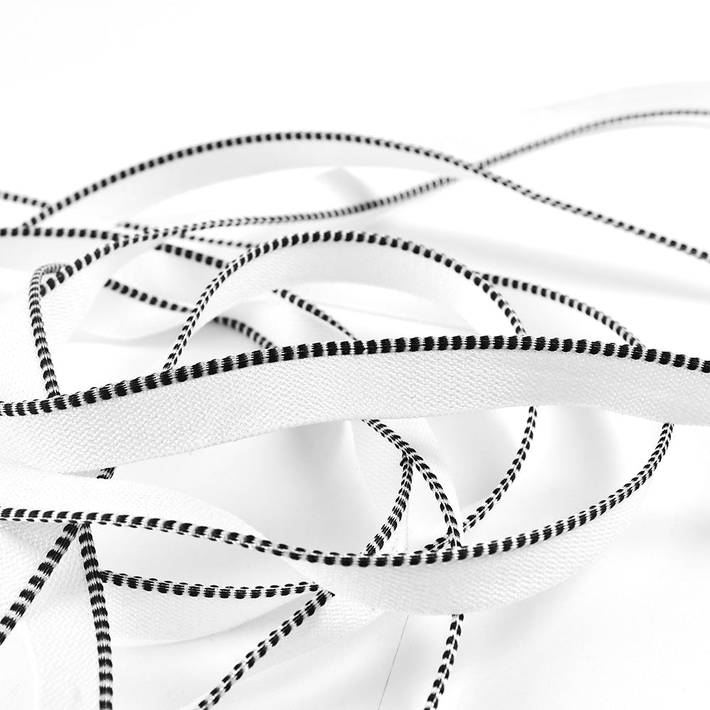 Weiße flache Schnürsenkel mit schwarzen gepunkteten Rändern, die sich auf weißem Grund verheddern und an ein Design von Alexandra Renke erinnern, das aus dem Buchrücken eines edlen Hardcovers hervorschaut.