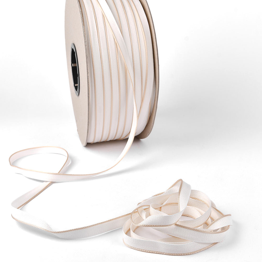 Alexandra Renke's weißes Satin-Kapitalband mit Goldrand auf einer Spule, teilweise lose vorgerollt - ideal, um Buchrücken oder Hardcover-Bücher zu veredeln.