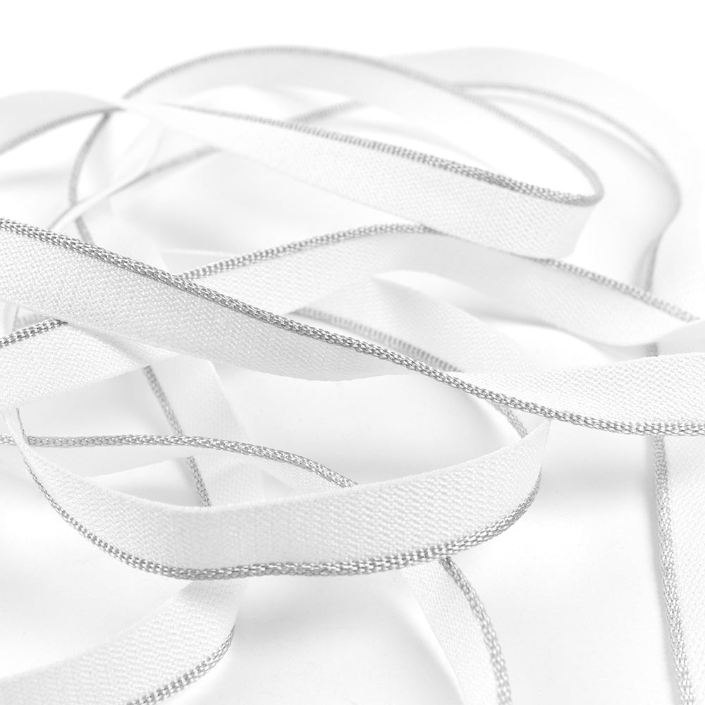 Alexandra Renkes weißes Band mit silbernen Rändern, das an einen Kapitalband in Hardcover-Büchern erinnert, ist locker vor einem weißen Hintergrund angeordnet.