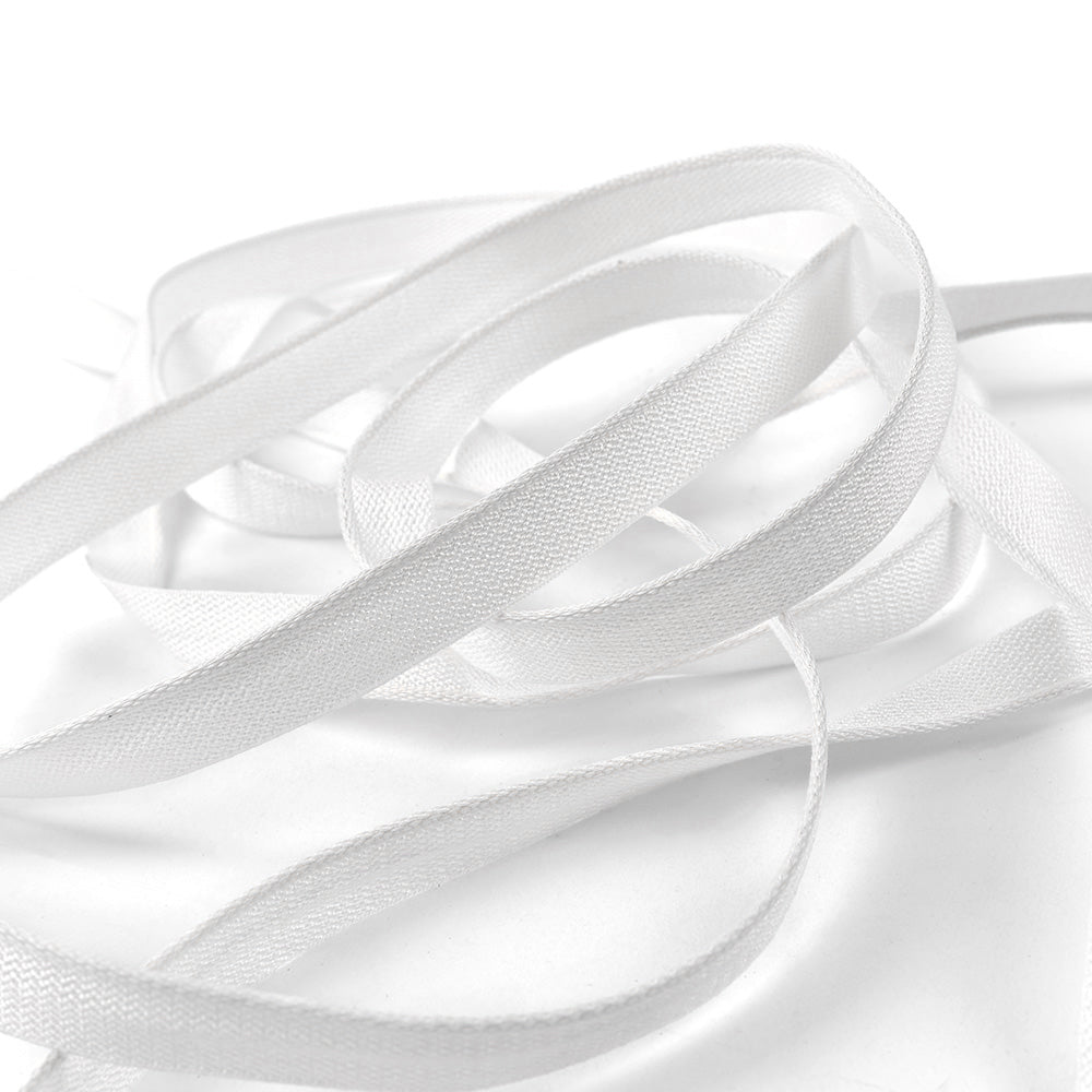 Ein weißes, flaches Band von Alexandra Renke, das an ein Kapitalband erinnert, ist locker auf einer weißen Oberfläche mit weichen Schatten und einer glatten Textur aufgewickelt.