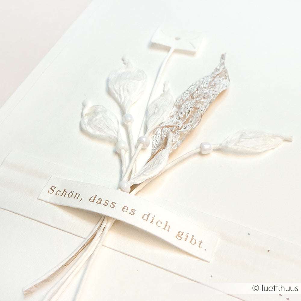 Eine zarte weiße Karte von Paperphine mit getrockneten Blumen und dem deutschen Text "Schön, dass es dich gibt" - perfekt für Bastelprojekte oder zum Veredeln von Geschenkverpackungen.