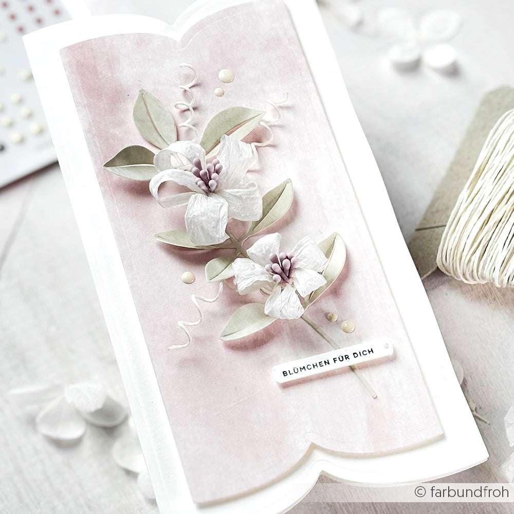 Handgefertigte Paperphine-Karte mit weißen Papierblumen und Blättern auf zartrosa Hintergrund, beschriftet mit BLÜMCHEN FÜR DICH-ideal für Bastelprojekte oder als besondere Note beim Verpacken von Geschenken.