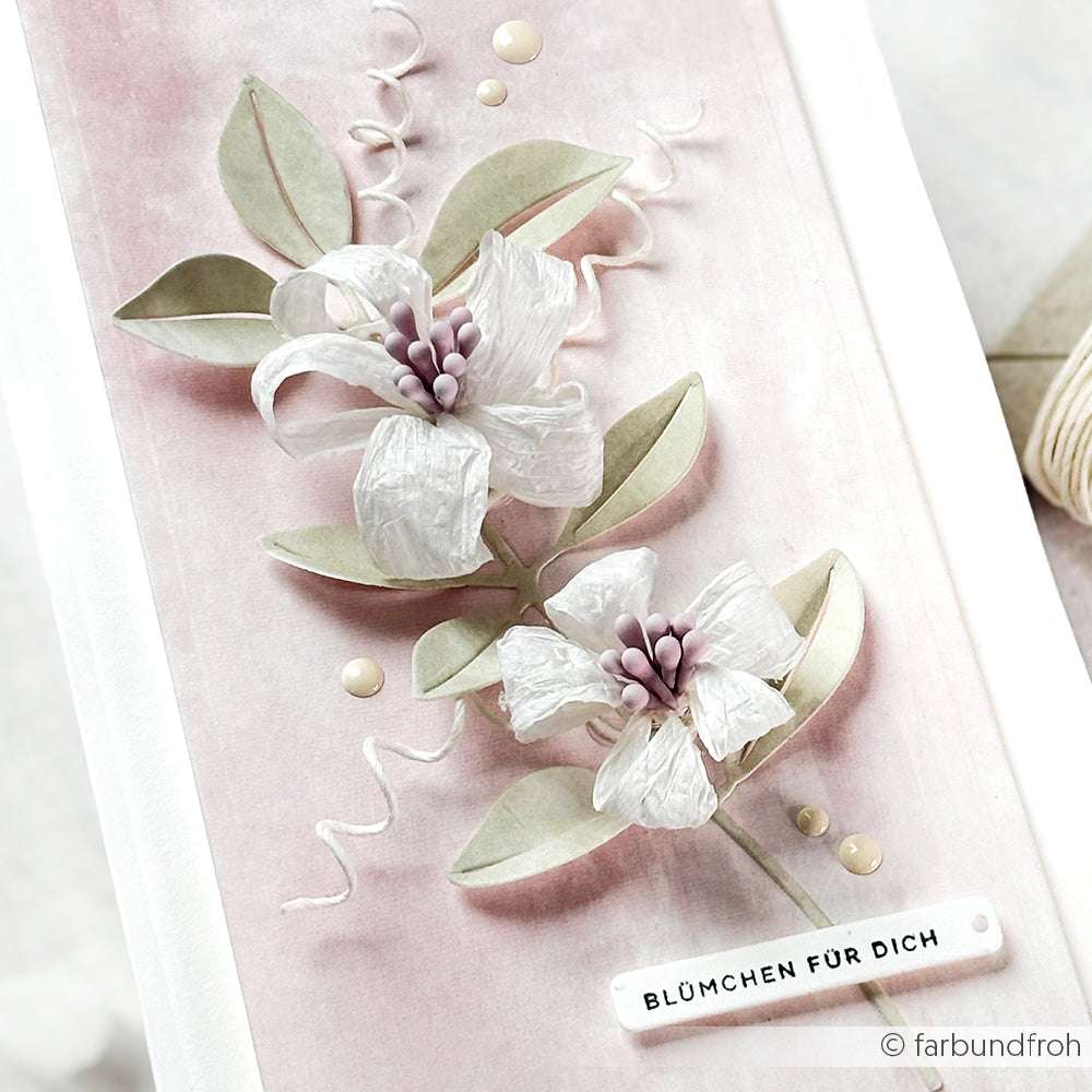 Handgefertigte Paperphine-Karte mit zwei weißen Papierblumen, grünen Blättern und einem "BLÜMCHEN FÜR DICH"-Etikett auf rosa - ideal für Bastelprojekte oder als einzigartige Geschenkverpackung für einen besonderen Menschen.