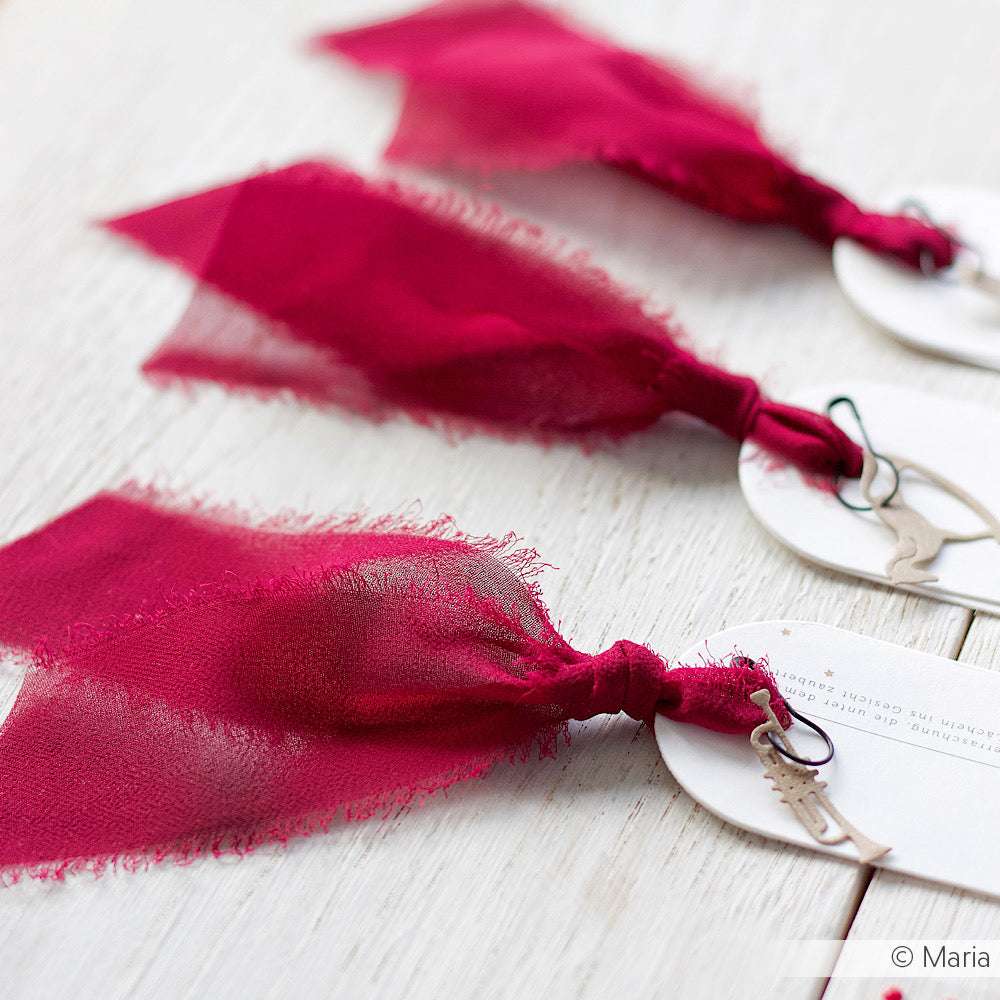 Drei runde weiße Anhänger von Vivant Decorations BV, jeder mit einem tiefroten Chiffonband und einem silbernen Anhänger - ideal für Bastelprojekte oder stilvolle Deko Ideen - auf einer weißen Holzoberfläche.