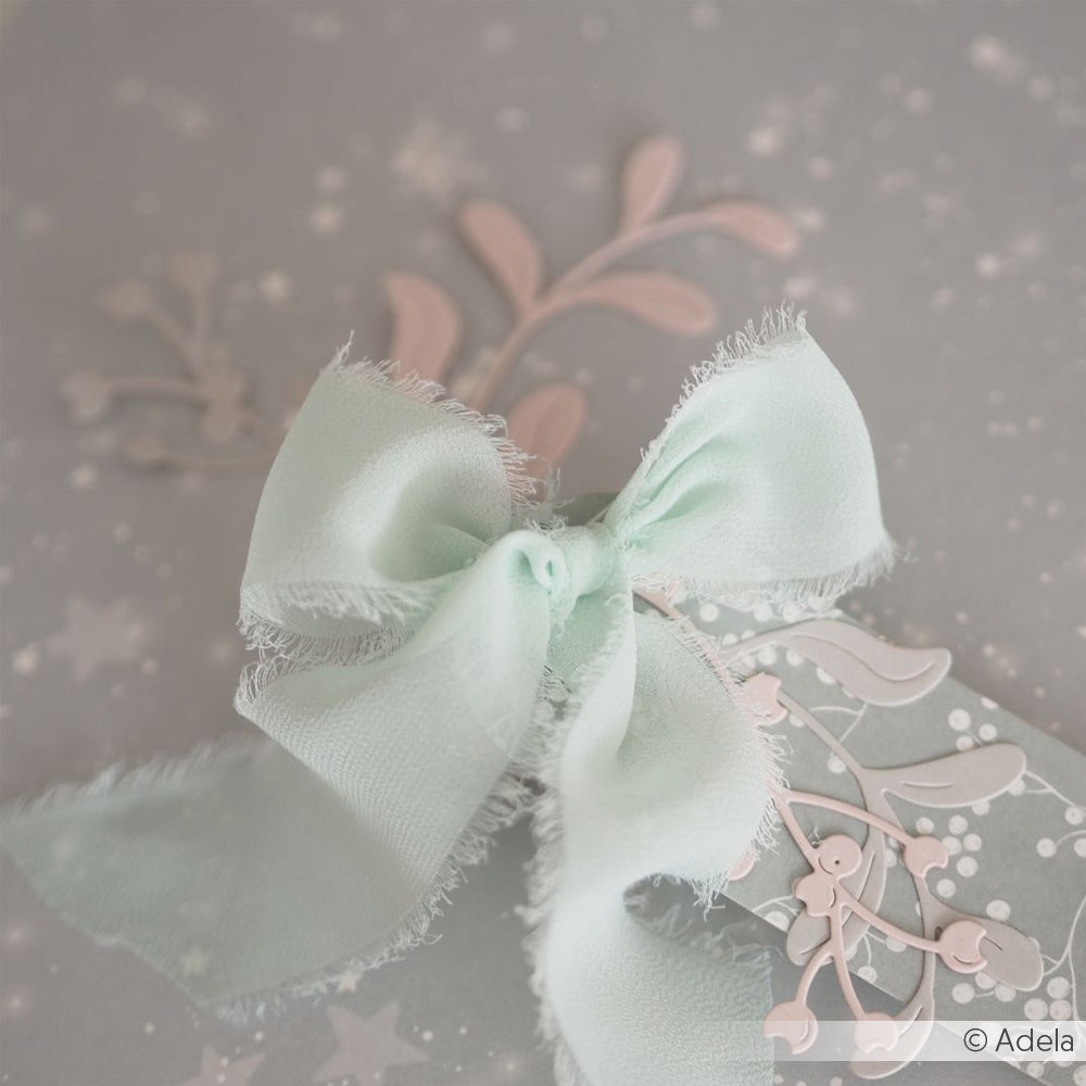 Eine zartgrüne Chiffonbandschleife auf einer grauen Karte mit zarten rosa und weißen Blumenmustern von Vivant Decorations BV - ein charmanter Akzent für Bastelprojekte oder inspirierende Deko Ideen.