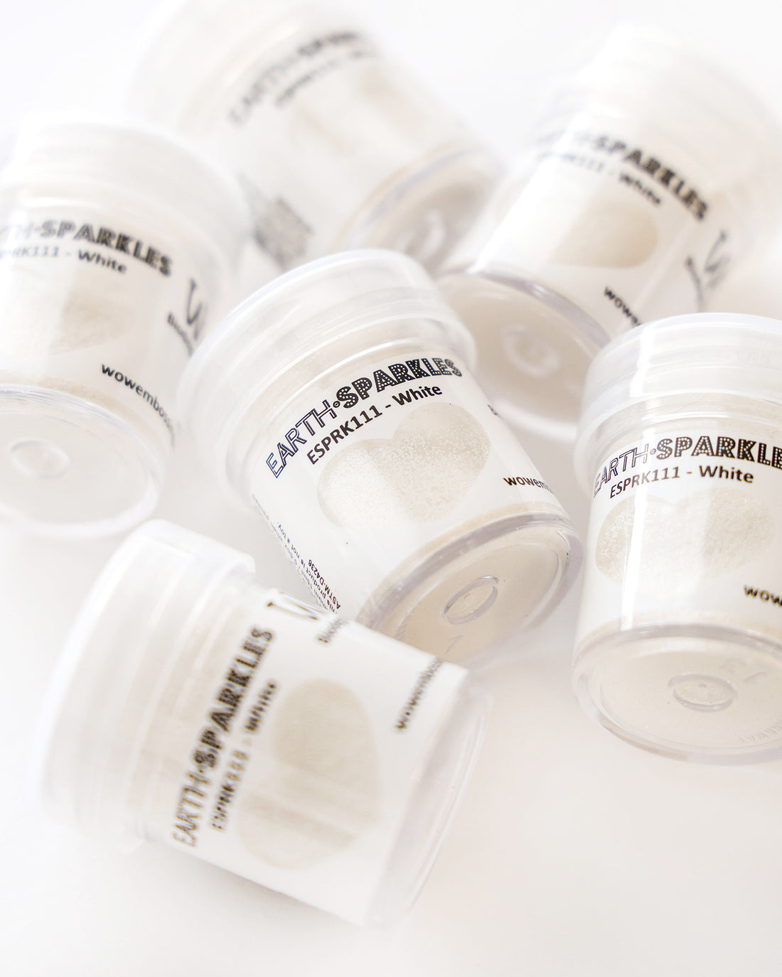 Kleine durchsichtige Gläschen mit WOW! Earth Sparkles weißem Glitter auf einer weißen Fläche.