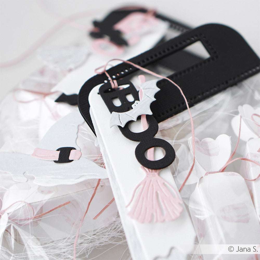 Halloween-Dekoration mit Buchstaben BOO, Fledermaus, Hexenhut und rosa Besen auf weißem Hintergrund, gestaltet mit Alexandra Renke DieCut Systeme und Motivstanze Etikett Boo für detaillierte Akzente.