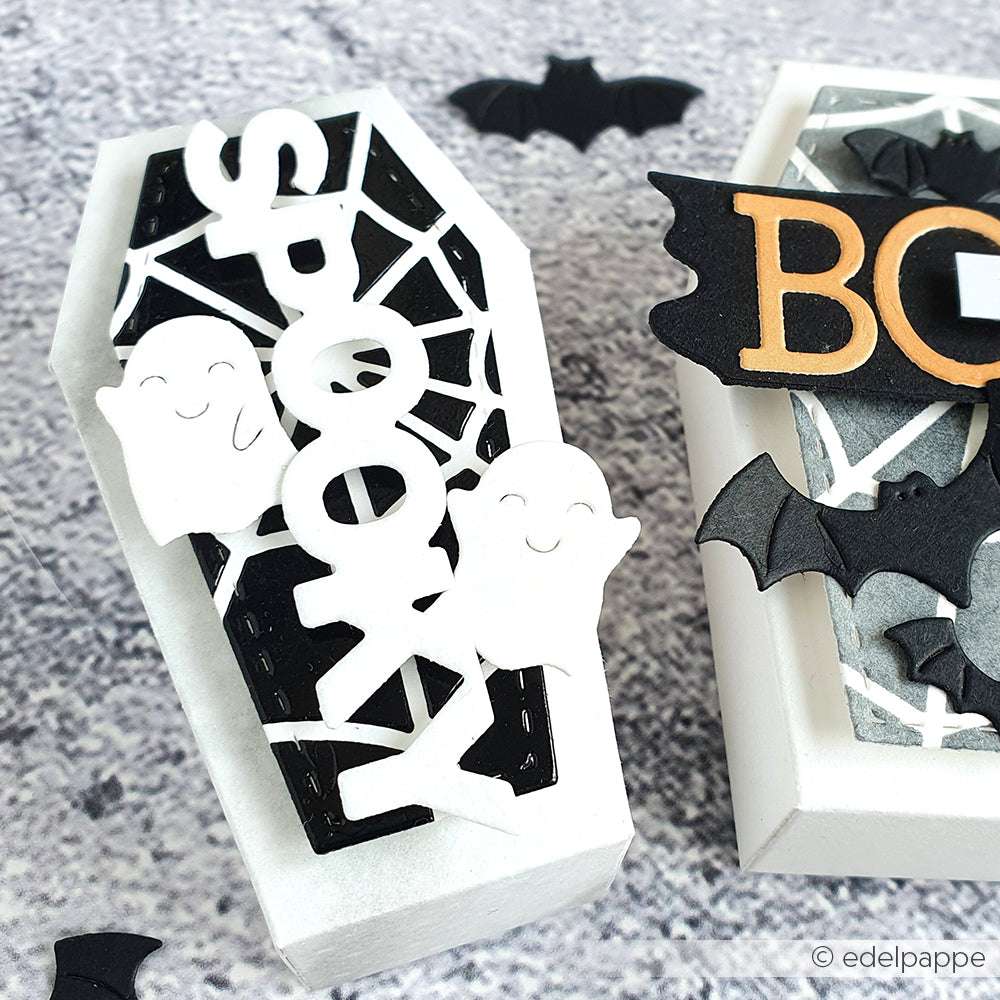 Weiße Halloween-Schachtel in Sargform mit gruseligen Details - zwei Gespenster, Spinnennetz, Fledermäuse - hergestellt mit Alexandra Renke Motivstanze Sechs kleine Gespenster DieCut System auf grauem Untergrund. Ideal für Stanzen für Designpapier-Projekte.