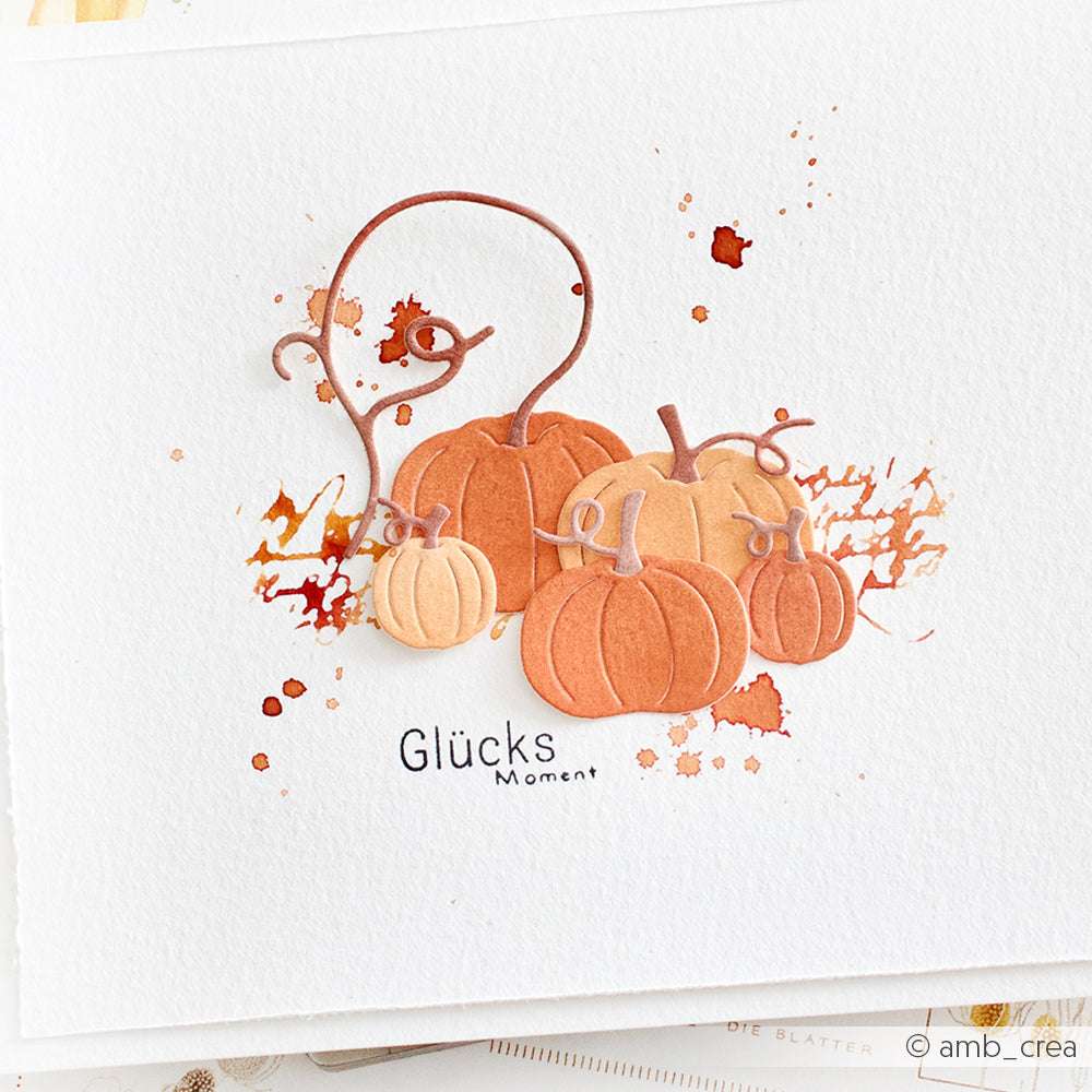 Kürbisse im Aquarell-Stil mit braunen Ranken und orangefarbenen Spritzern, darunter "Glücks Moment" - ideal für Alexandra Renke-Fans oder als Inspiration für Ihr nächstes Motivstanze Kürbis Set-Projekt.