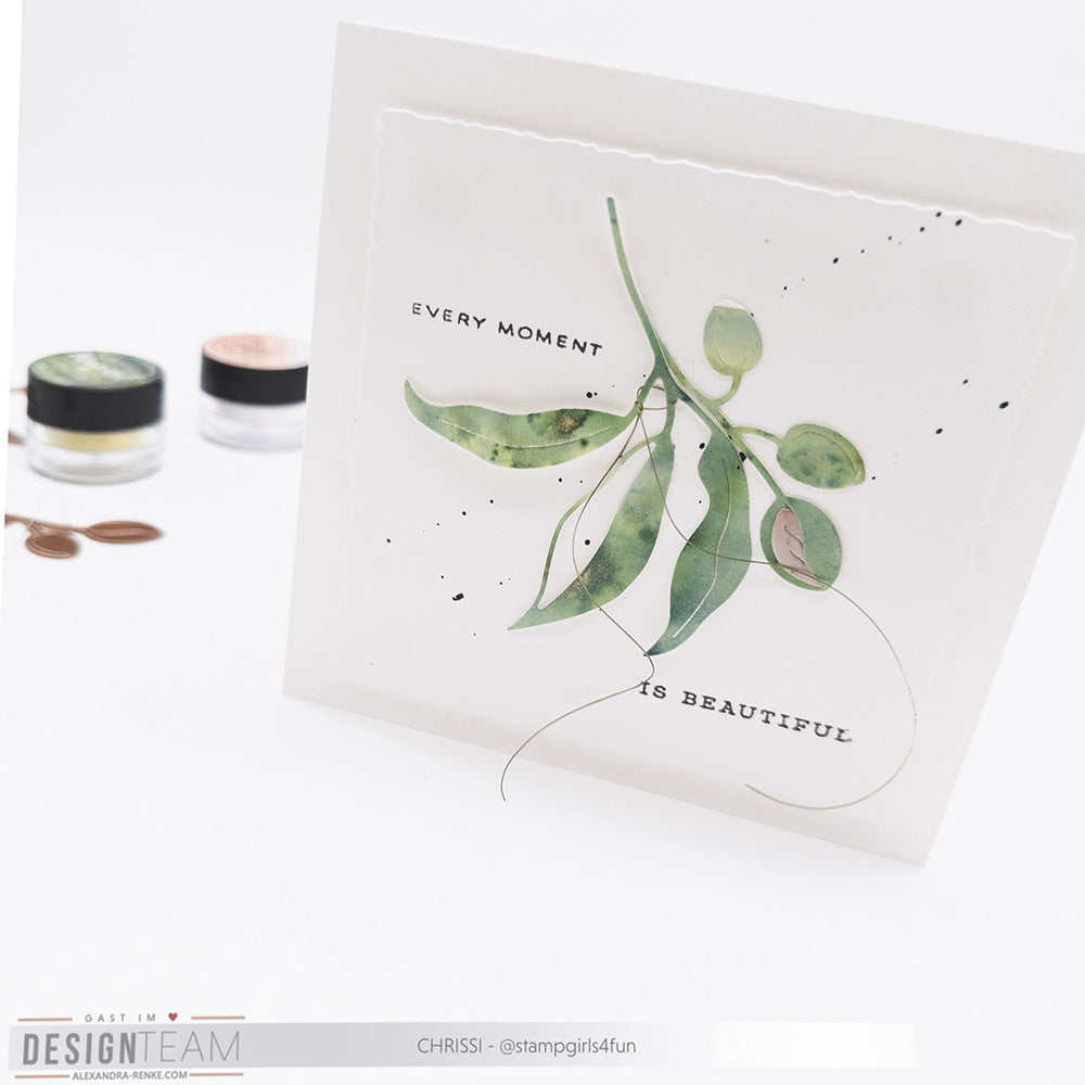 Eine handgefertigte Karte von Alexandra Renke mit grünen Blättern, die mit Designpapieren und der Motivstanze Mandelzweig Duo hergestellt wurde, zeigt "Every moment is beautiful" auf weißem Hintergrund.