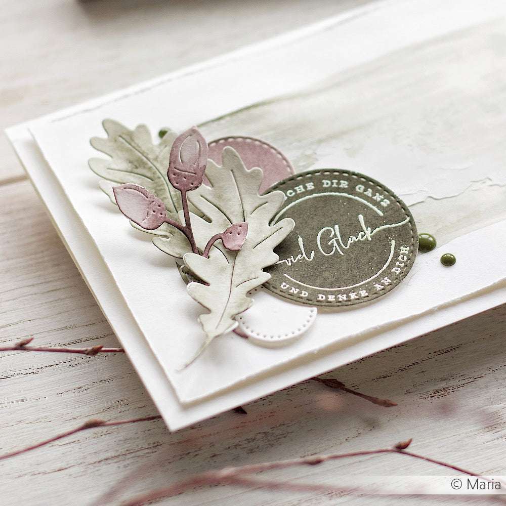 Handgefertigte Karte von Alexandra Renke mit pastellfarbenen Blättern, Knospen und einem runden Anhänger auf weißem und grünem Aquarellhintergrund, mit eleganten gestempelten Details für einen raffinierten Look.