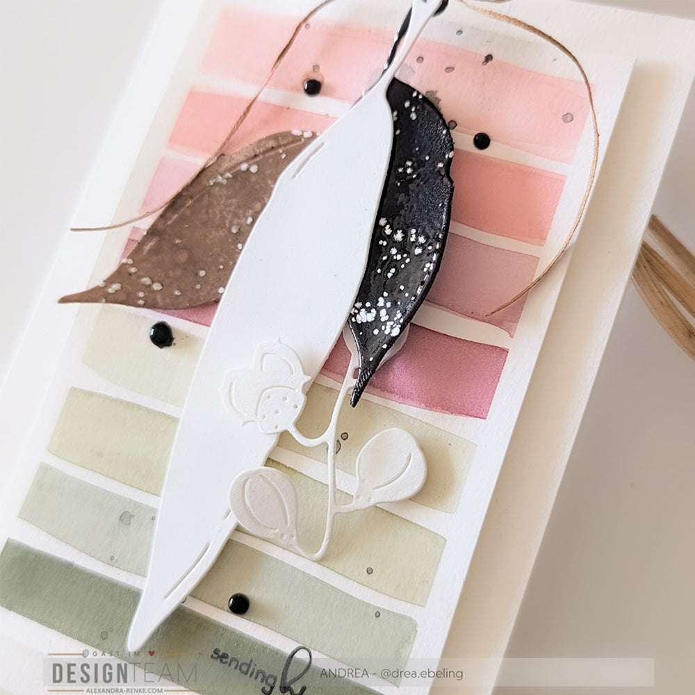 Handgemachte Karte mit geschichteten Papierblättern, die mit Alexandra Renke Designpapieren und DieCut Systemen über pastellfarbenen Aquarellstreifen in Rosa, Grün und Beige hergestellt wurden.