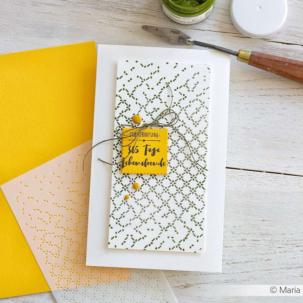 Handgefertigte Grußkarte mit grünen und gelben Akzenten auf einem weißen Tisch, daneben Briefumschläge, Bastelwerkzeug und Alexandra Renke Grundkarten creme-weiß mit klassischem Papier Haptik-ideal für Karten für Digitaldruck oder handschriftliche Notizen.