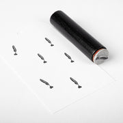 Ein schwarzer Alexandra Renke-Stempel sitzt neben gestempelten Mini Schreibfeder-Symbolen auf einem weißen Papieranhänger.