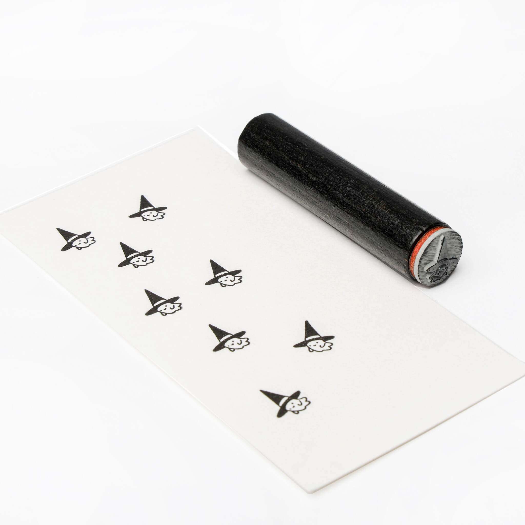 Ein schwarzer Alexandra Renke Stempel und Papier mit mehreren gestempelten Hexengesichtern in spitzen Hüten, ideal um eine skurrile Note hinzuzufügen oder Details mit dem Mini Schwarze Katze Stempel oder einem Akzent-Stempel hervorzuheben.