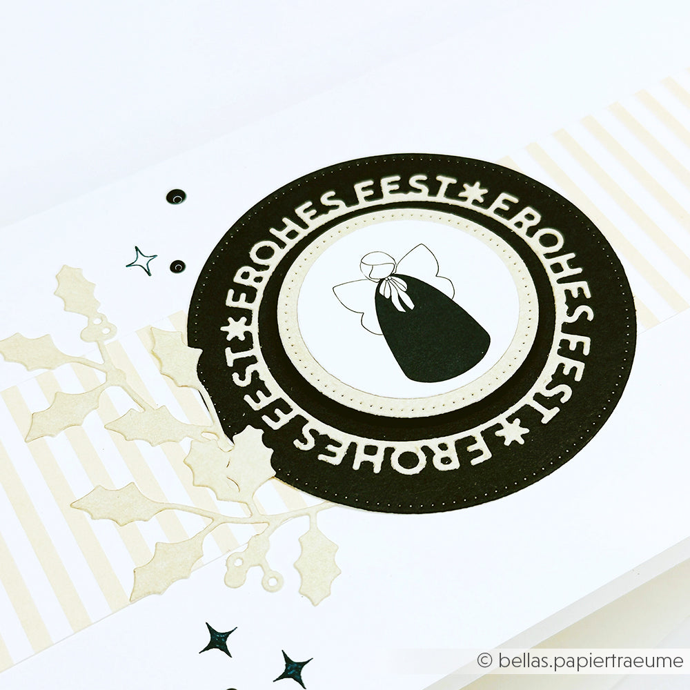 Runde Karte von Alexandra Renke mit dem Schriftzug "Frohes Fest", einer minimalistischen Stiller Engel-Grafik, Stechpalmenblättern und Sternenakzenten.