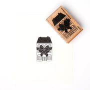 Ein Alexandra Renke Holzstempel mit Stempelgummi stempelt ein bezauberndes Festliches Schleifenhaus - ein Haus mit einer großen Schleife - auf knackig weißes Papier.