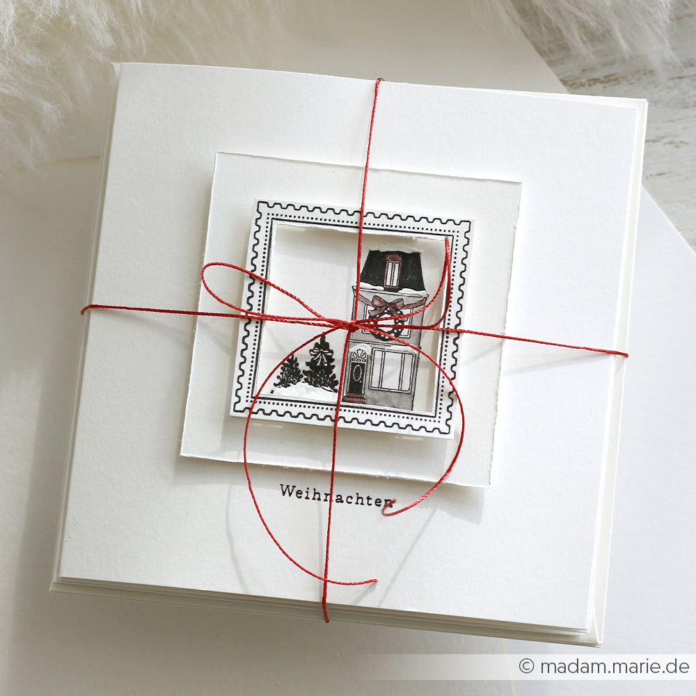 Weiße Grußkarte von Alexandra Renke mit einer schwarz-weißen Weihnachtsillustration, gebunden mit roter Schnur und der Aufschrift "Weihnachten". Ideal für Papierprojekte oder in Kombination mit Ihrem Lieblingsholzstempel für eine persönliche Note.