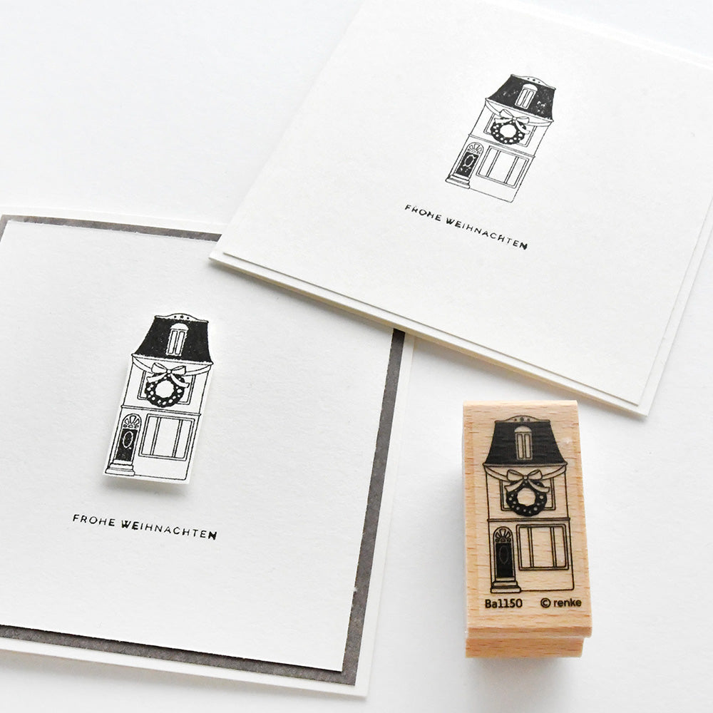 Ein Alexandra Renke Stempelgummi und zwei Karten mit einem schwarz-weiß illustrierten dekorierten Haus und "Frohe Weihnachten" - ideal für winterliche Papierprojekte.
