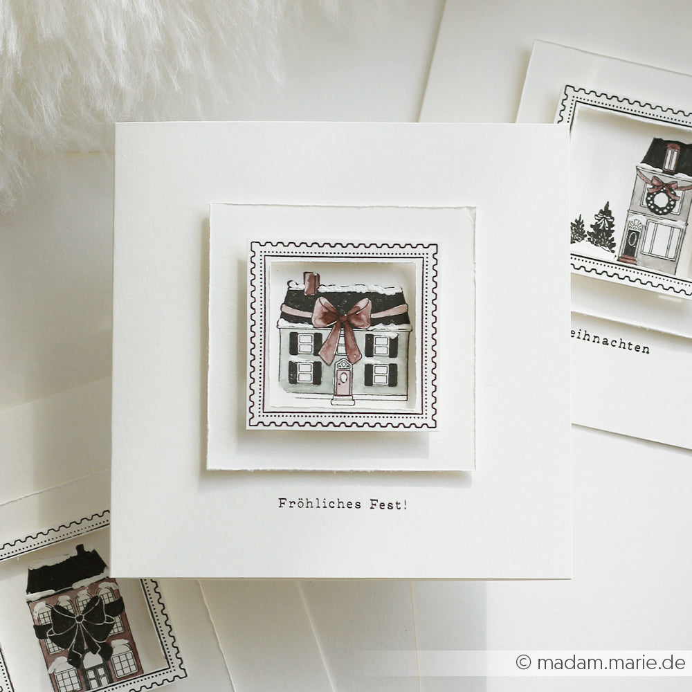 Eine handgefertigte Weihnachtskarte von Alexandra Renke mit einem Haus mit roter Schleife und "Fröhliches Fest!" darunter, gefertigt mit hochwertigen Holzstempeln und Stempelmotiven für eine elegante, festliche Note.
