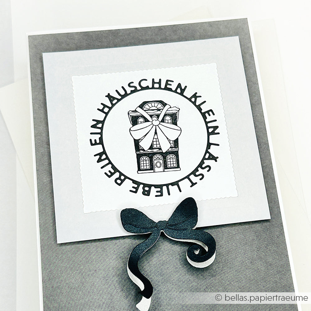 Die handgefertigte Karte von Alexandra Renke zeigt eine Haus-Illustration und einen deutschen Text in einem Kreis mit der Aufschrift "Ein kleines Häuschen, fast lieber" - liebevoll gestaltet mit Stempelgummi für eine einzigartige Note.