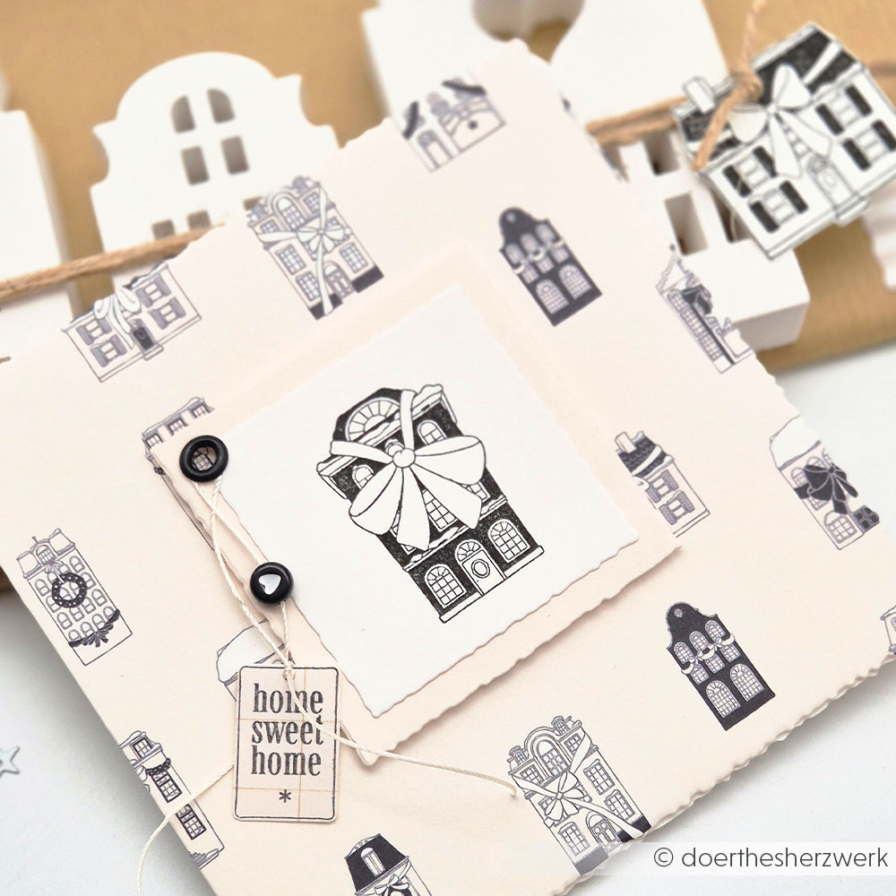 Grußkarte von Alexandra Renke mit schwarz-weißen Haus-Illustrationen, Buttons, einem "Home Sweet Home"-Anhänger und Zwillingen - ideal für Papierprojekte oder zur Präsentation von Stempelgummi-Designs.