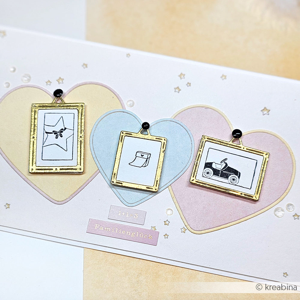 Drei kleine goldgerahmte Skizzen auf pastellfarbenen Herzen - ein Stern, ein Hut und ein Kinderwagen - sind perfekte Akzente für Ihre Alexandra Renke Mini Kalender Stempel oder Holzstempel Projekte mit Ihren Lieblings Stempelkissen.