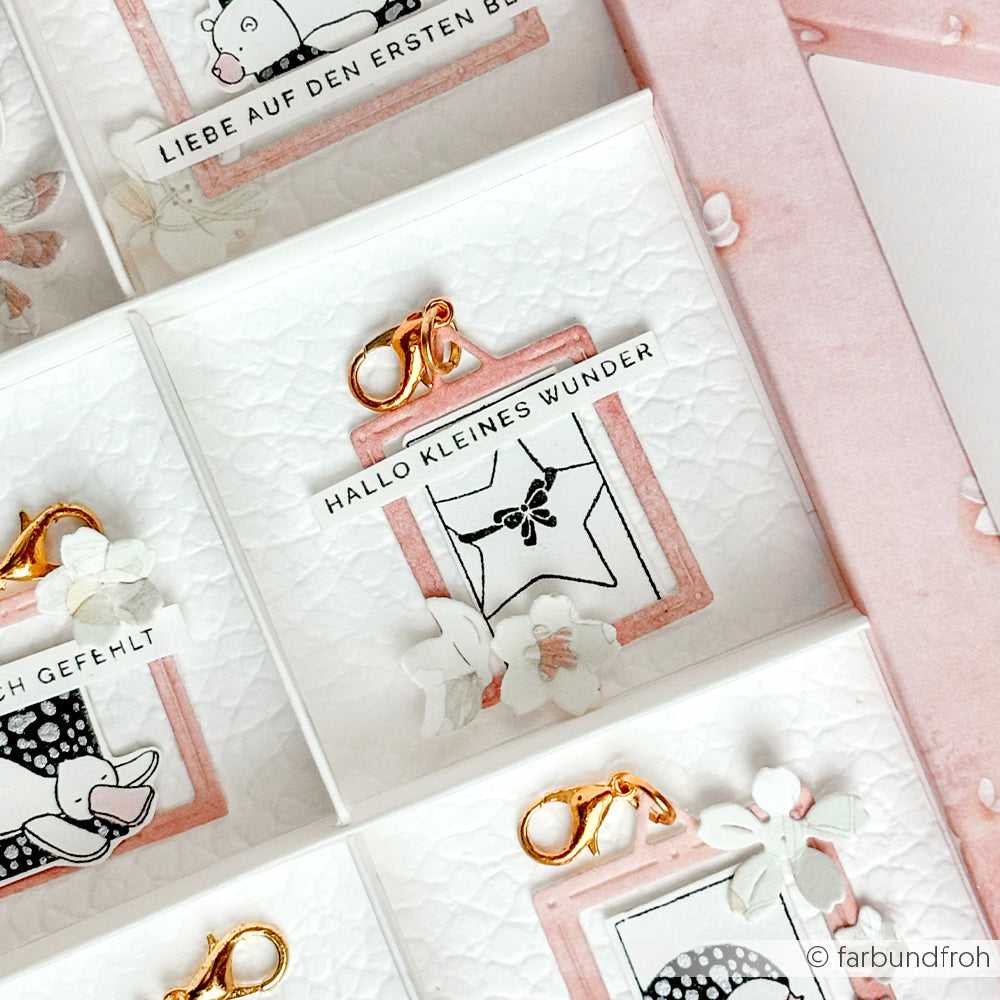 Eine rosa-weiße Karte von Alexandra Renke mit goldenen Verschlüssen, zarten Blumen und dem Text "HALLO KLEINES WUNDER" - perfekt für Papierprojekte oder zur Kombination mit Ihrem Lieblingsholzstempel.