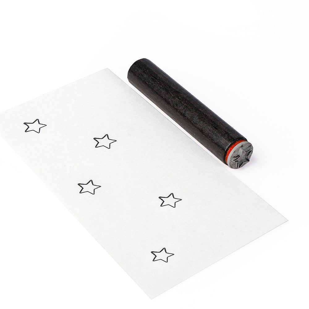 Ein schwarzer Holzstempel in Sternform von Alexandra Renke und ein Blatt Papier mit scharfen schwarzen Sternkonturen, jeweils mit einem Stempelkissen gestempelt.