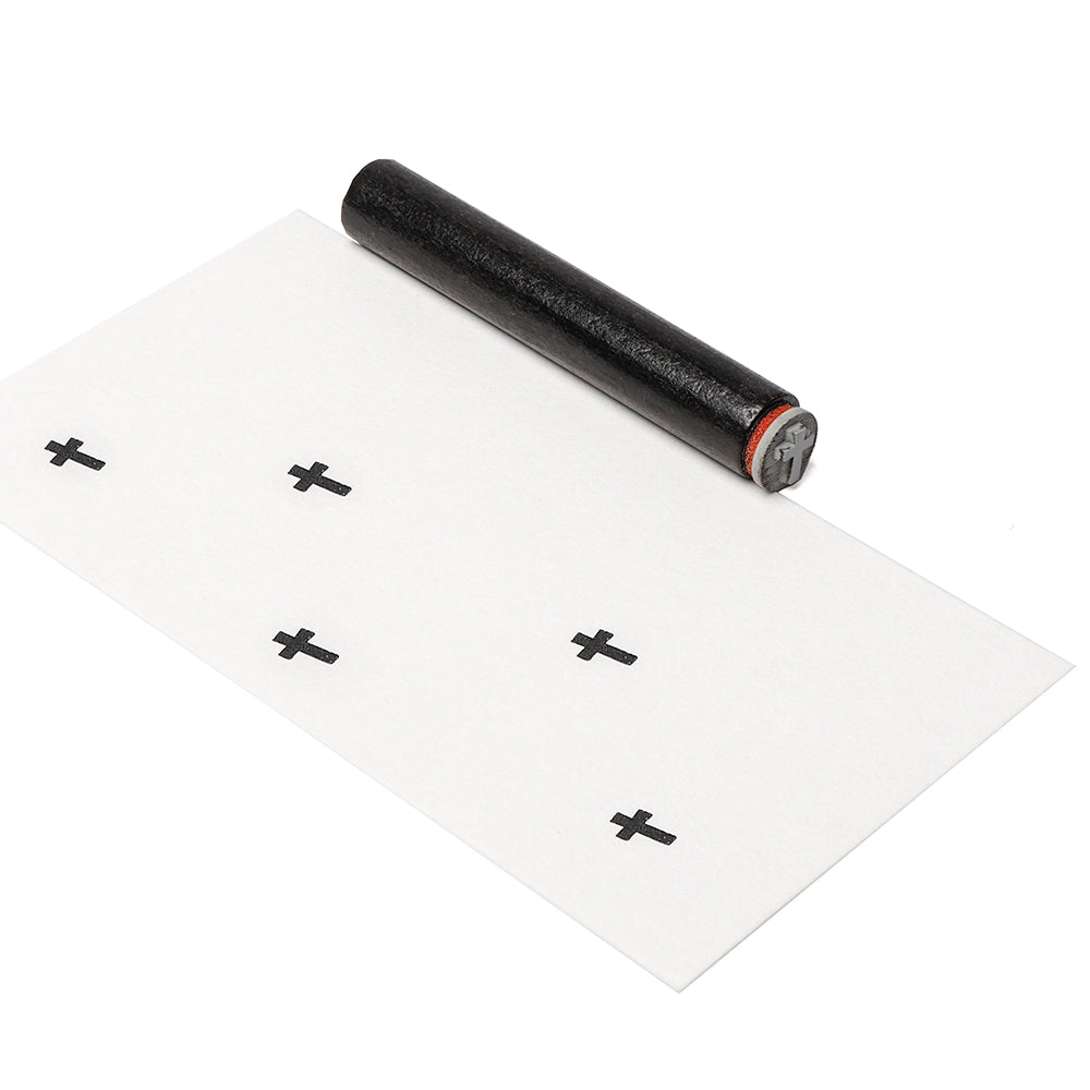 Eine schwarze Batterie rollt auf dem Papier wie ein Mini Kreuz Stempel von Alexandra Renke und hinterlässt beim Drucken fette schwarze Pluszeichen.