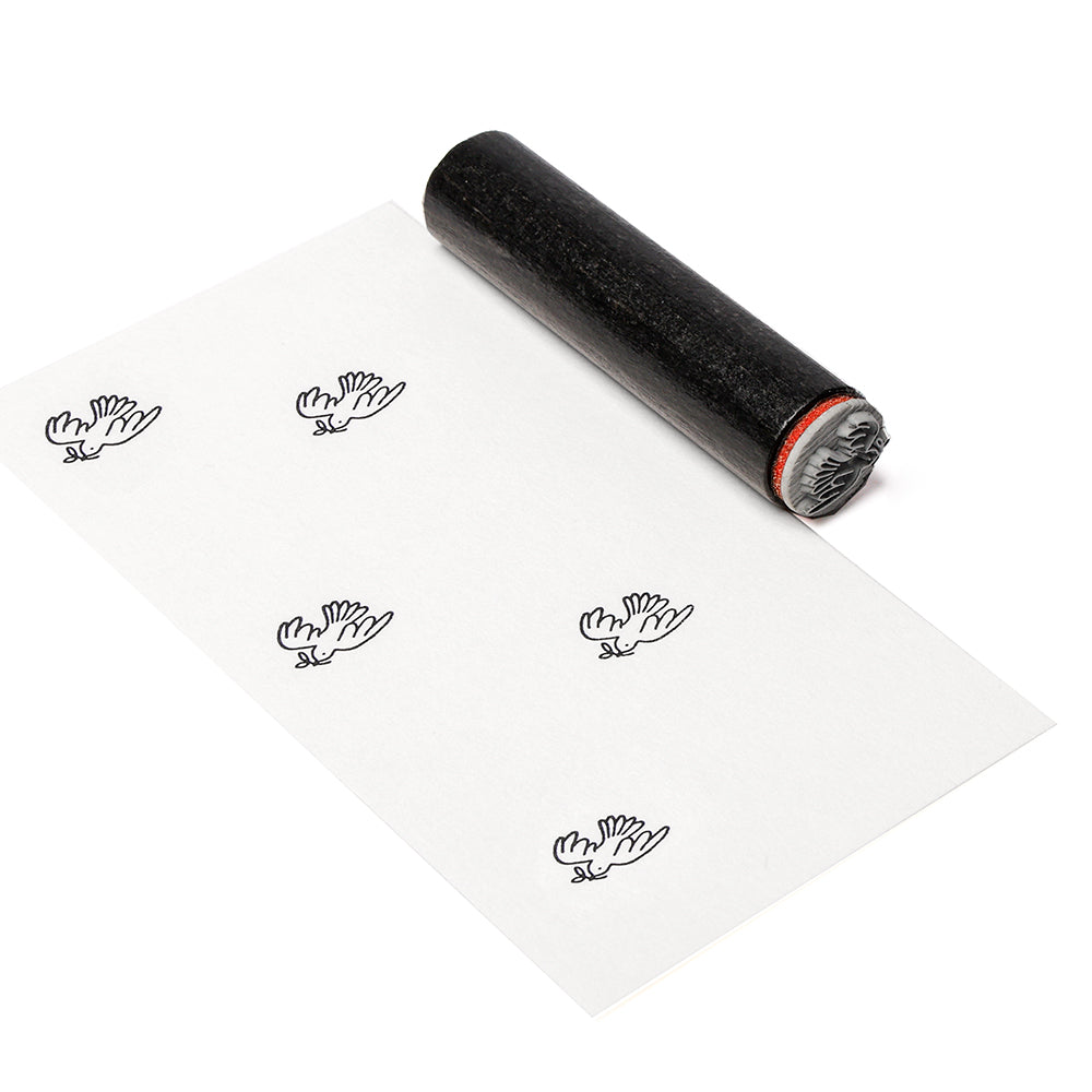 Eine Alexandra Renke Walze mit schwarzer Tinte druckt mehrere Handsymbole auf ein weißes Blatt Papier.