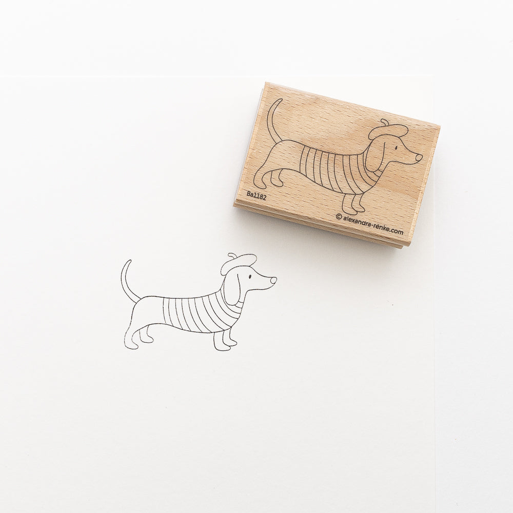 Der Stempel von Alexandra Renke und sein Aufdruck zeigen eine einfache Strichzeichnung eines Dackels in einem gestreiften Hemd - ideal als Holzstempel zum Besticken oder um Ihren Stickprojekten Charme zu verleihen.