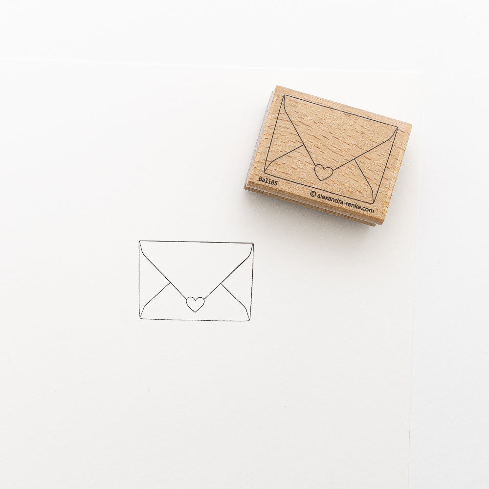 Ein Holzstempel zum Besticken von Alexandra Renke hinterlässt einen Umschlag mit einem Herz-Siegel-Aufdruck - ideal für Stickprojekte mit Ihrer Lieblings-Stempelfarbe für Stoff auf weißem Papier.