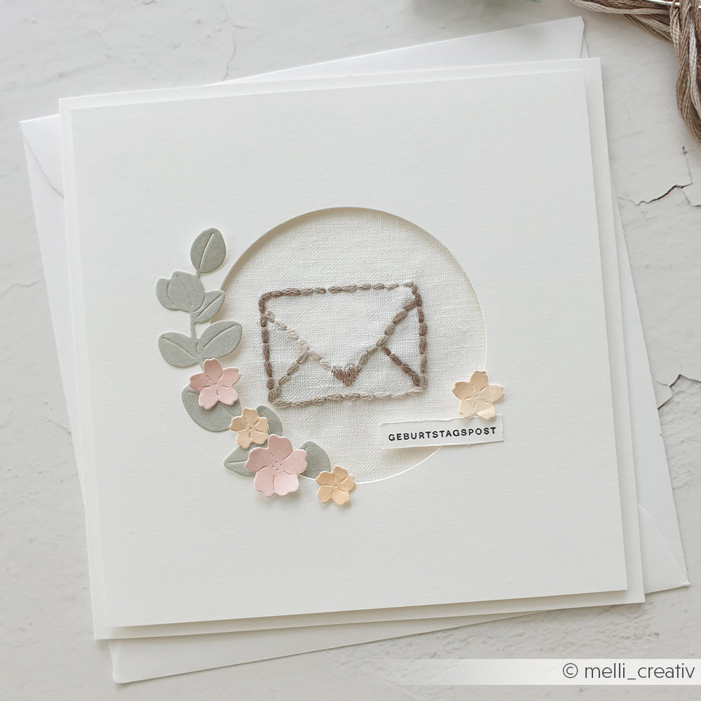 Handgefertigte Geburtstagskarte von Alexandra Renke mit einem bestickten Umschlag mit pastellfarbenen Blumen und Blättern auf weißem Hintergrund - ideal zum Verschenken mit Ihren Lieblingsstickvorlagen Stempel für kreative Stickprojekte.
