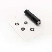 Ein schwarzer Holzstempel und eine weiße Karte, die mit vier schwarzen Blumenmustern mit der Nummer 8 bestempelt sind - perfekt für Papierprojekte oder um Ihre Bastelarbeiten mit einem charmanten Alexandra Renke Stempel Mini Blumenknopf zu versehen.