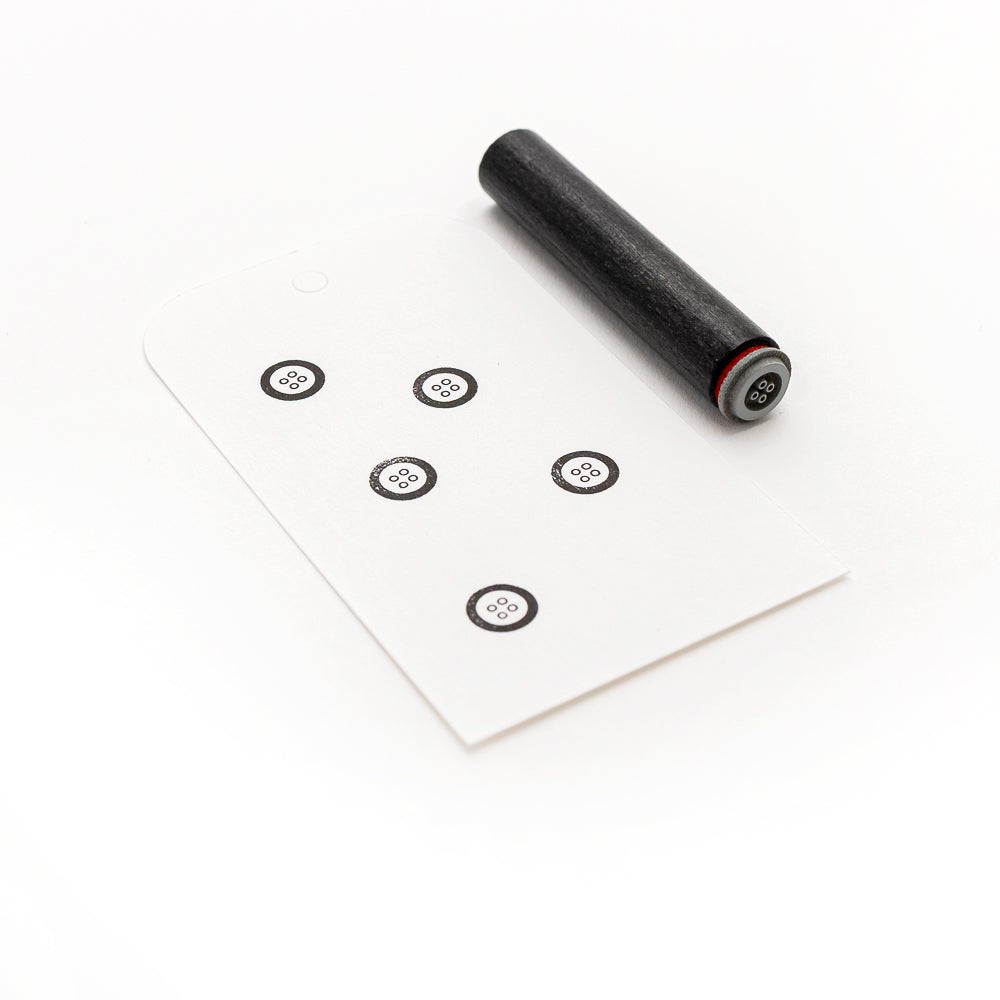 Ein schwarzer zylindrischer Alexandra Renke Mini Knopf Stempel wird neben eine weiße Karte gelegt, auf der sechs kleine schwarze Zielsymbole abgebildet sind.