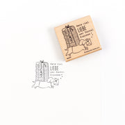 Ein Holzstempel und sein Abdruck, der einen Dackel zeigt, der einen Stapel Geschenke trägt, mit dem deutschen Text „Ganz viel LIEBE per Dackel-Express“ – eines von vielen Stempelmotiven.