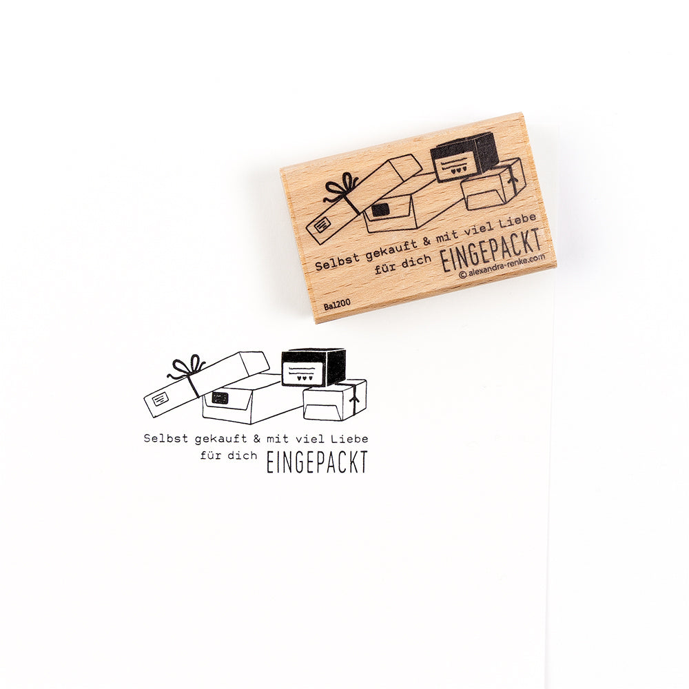 Ein hochwertiger Holzstempel aus Holz mit einem Stempelabdruck, der gestapelte Geschenkboxen und den Text „Selbst gekauft & mit viel Liebe EINGEPACKT“ zeigt.