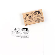 Ein hochwertiger Holzstempel aus Holz mit einem Stempelabdruck, der gestapelte Geschenkboxen und den Text „Selbst gekauft & mit viel Liebe EINGEPACKT“ zeigt.