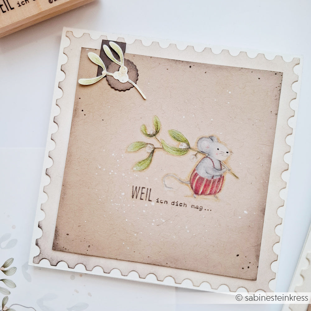 Eine Maus, die einen Mistelzweig mit deutscher Aufschrift trägt – perfekt für Ihre Holzstempel-Papierprojekte.