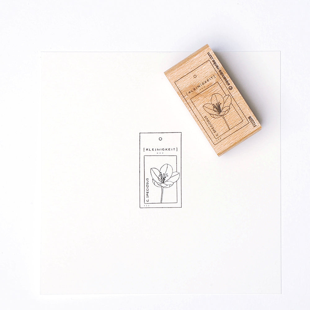 Ein Holzstempel von Alexandra Renke und sein Aufdruck zeigen eine einfache Blume mit deutschem Text auf weißem Papier - perfekt für Papierprojekte.
